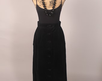 May include: A black velvet skirt with a button-up front and a high waist. The skirt is long and flowing, and it is being displayed on a mannequin.