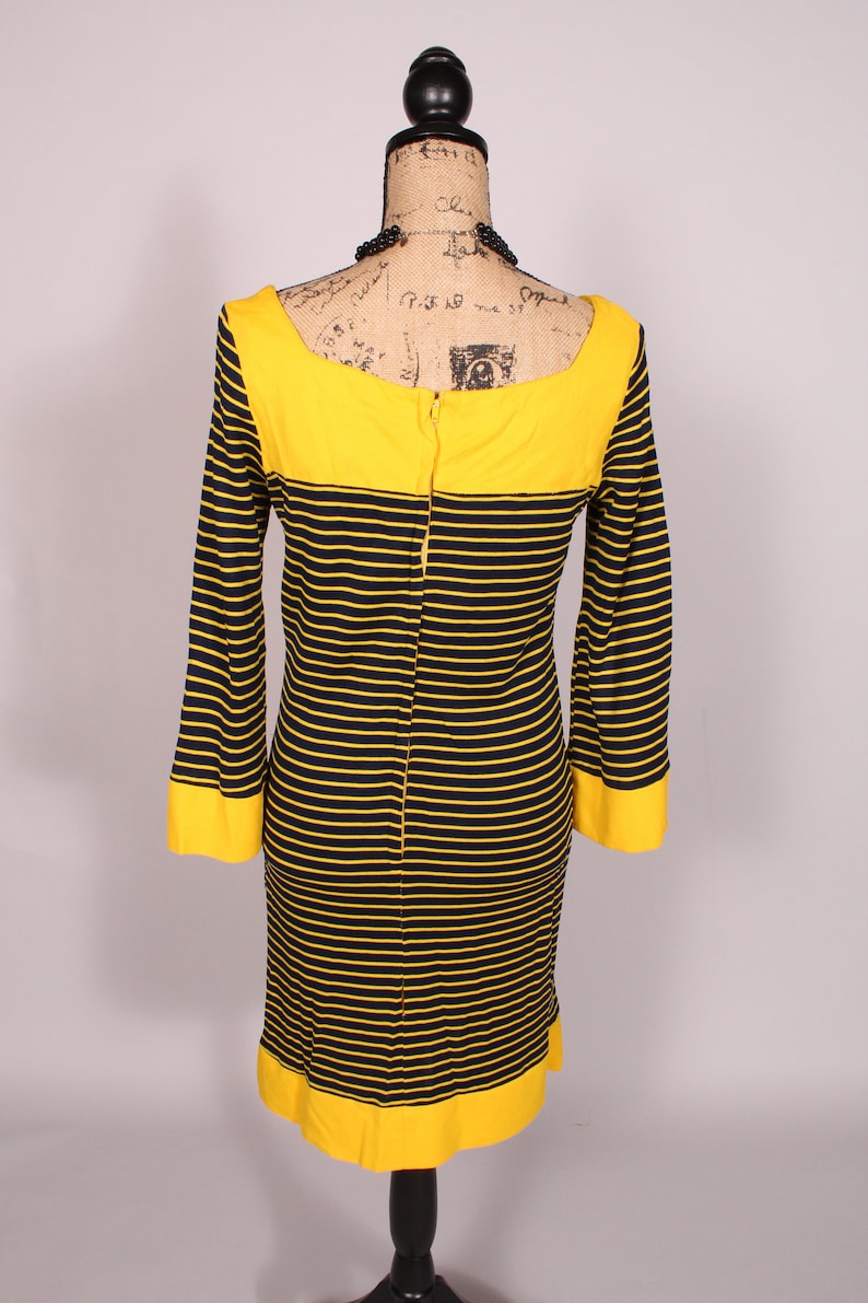 Puede incluir: Un vestido de rayas amarillas y negras con cuello y pu&ntilde;os amarillos. El vestido tiene una cremallera en la espalda.