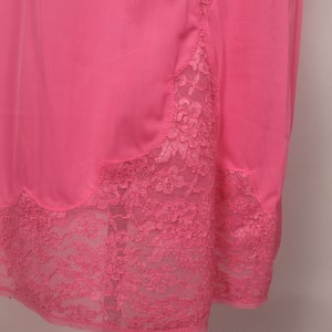 May include: A pink slip with a lace trim. The lace is a delicate floral pattern and is the same color as the slip.