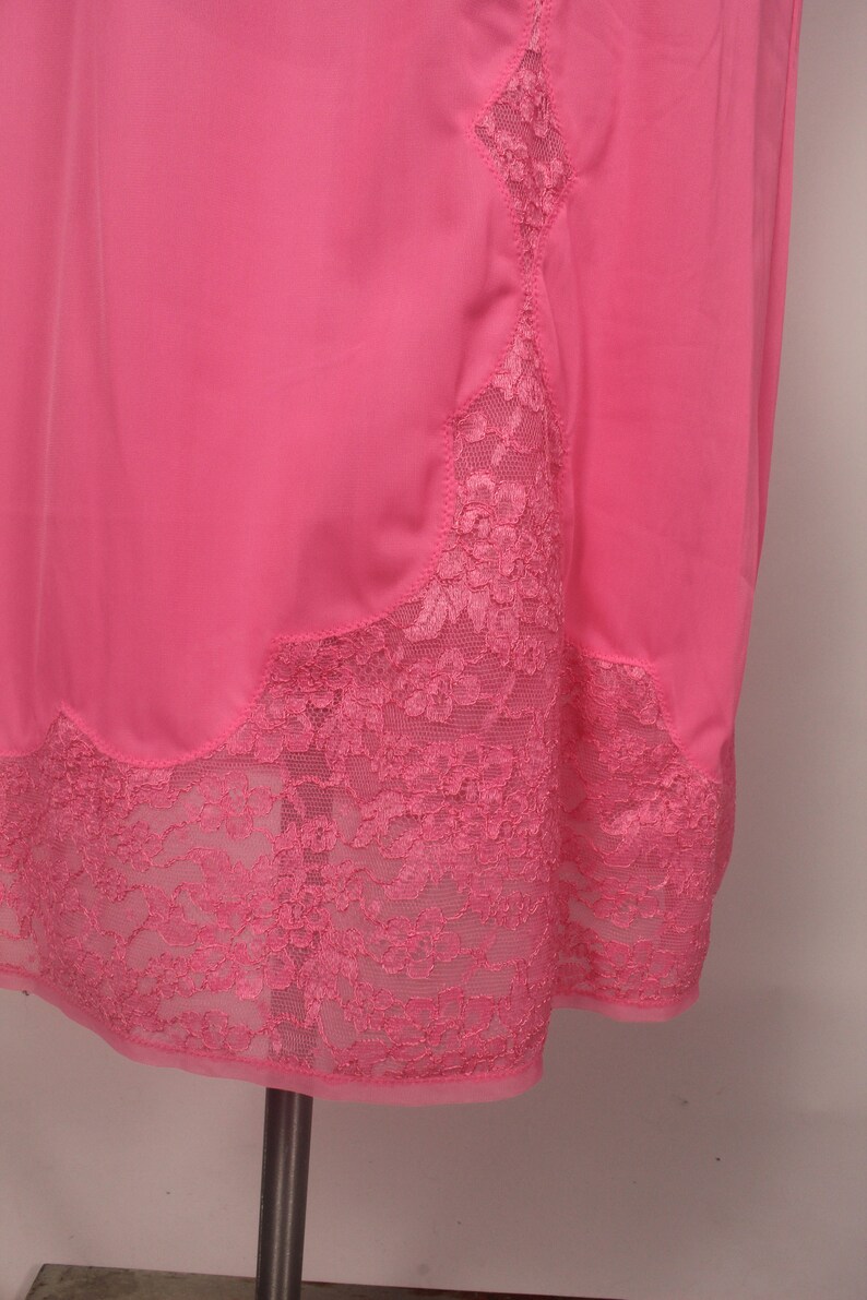 May include: A pink slip with a lace trim. The lace is a delicate floral pattern and is the same color as the slip.