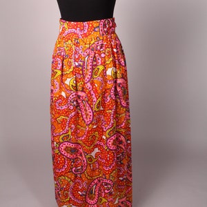 May include: A long, flowing skirt with a paisley print in shades of orange, pink, and yellow. The skirt has a high waist and a gathered design.