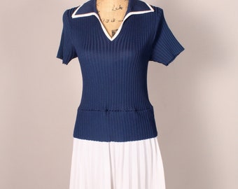May include: A navy blue and white dress with a ribbed top and a pleated skirt. The top has a white collar and short sleeves.
