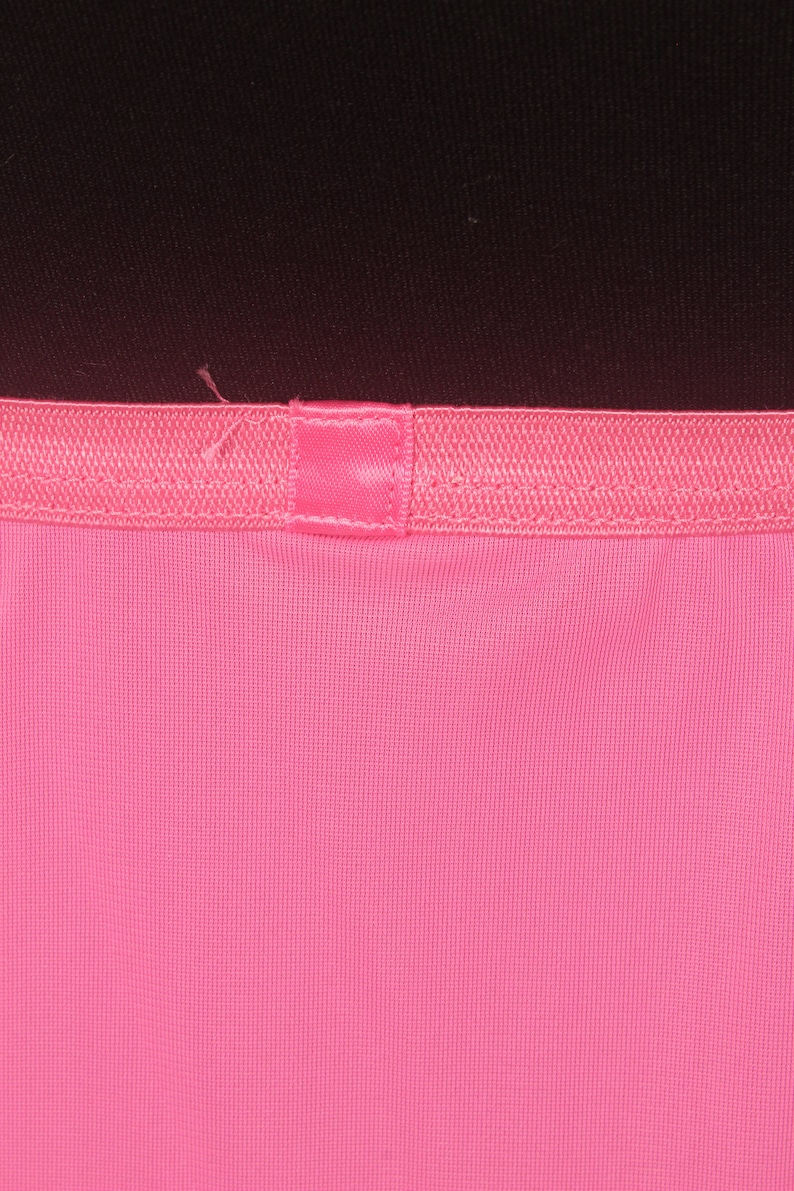 May include: Close-up of a pink fabric with a pink ribbon sewn across the top.