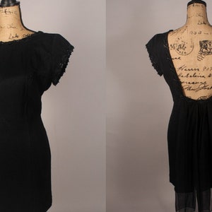May include: A black sleeveless dress with a lace trim on the neckline and sleeves. The dress has a low back with a sheer panel.
