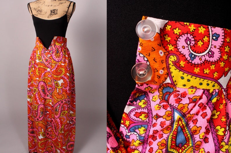 May include: A long, flowing skirt with a paisley print in shades of pink, orange, and yellow. The skirt has a black top and buttons down the front.