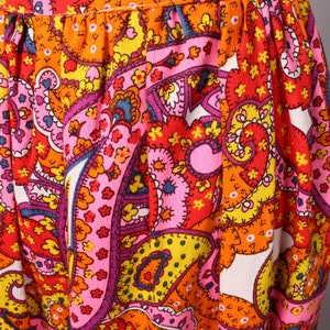 May include: A pink, orange, yellow, and red paisley print fabric with a white background. The fabric has a textured surface and is made of a soft, comfortable material.