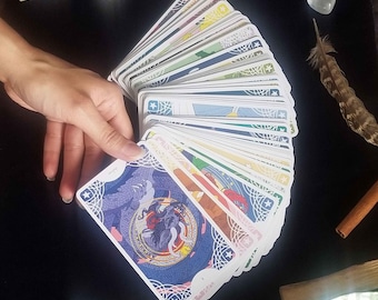 May include: A fan of tarot cards featuring intricate blue, white, and red graphic illustrations on the back. The cards are arranged in a semi-circular spread, showcasing various colorful designs on the front faces, including a prominent dragon motif.