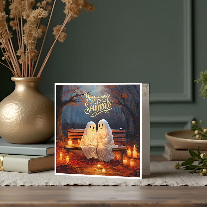 May include: A greeting card featuring two glowing ghosts sitting on a bench in a forest setting. The card has the text "You are my Soulmate" in gold lettering.