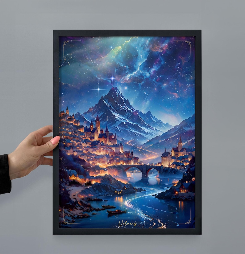 Puede incluir: Una impresi&oacute;n art&iacute;stica enmarcada que representa un paisaje de fantas&iacute;a con un pueblo junto a un r&iacute;o, bajo un cielo nocturno estrellado. La obra de arte presenta un puente, monta&ntilde;as y edificios iluminados. La impresi&oacute;n est&aacute; sujeta por una mano.