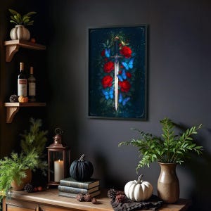 May include: Framed artwork featuring a sword piercing a cluster of red roses, with blue butterflies scattered around. The background is a dark, moody blue. The artwork is in a black frame, adding a touch of elegance to the piece.