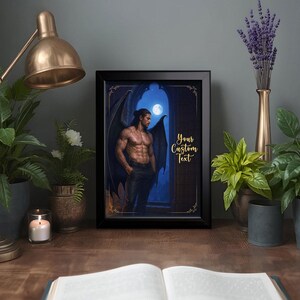 May include: A framed print featuring a muscular figure with dark wings, standing in front of a moonlit archway. The artwork has a fantasy theme, with the text "Your Custom Text" in gold script. The frame is black, and the print is displayed on a wooden surface.