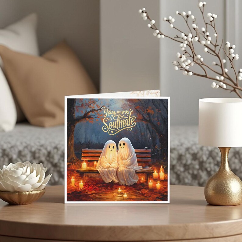 May include: A greeting card featuring two cartoon ghosts sitting on a bench in a forest setting. The ghosts are glowing and smiling. The text on the card reads "You are my Soulmate".