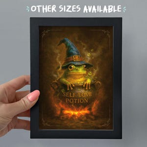 May include: Framed artwork depicting a frog in a wizard's hat, emerging from a cauldron. The cauldron reads "SELF LOVE POTION". The image has a dark, atmospheric background and a decorative border. The text "OTHER SIZES AVAILABLE" is at the top.
