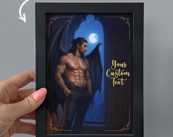 May include: Black framed art print featuring a muscular man with dark wings, standing in front of a moonlit window. The print includes the text "ADD CUSTOM TEXT" and "Your Custom Text" in gold lettering.