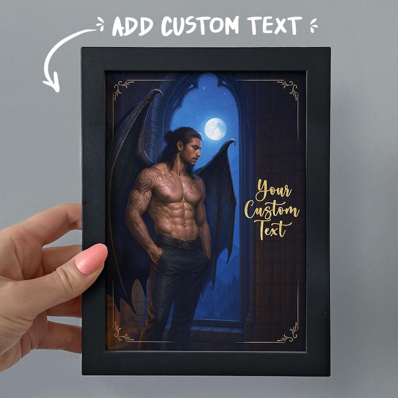 May include: Black framed art print featuring a muscular man with dark wings, standing in front of a moonlit window. The print includes the text "ADD CUSTOM TEXT" and "Your Custom Text" in gold lettering.