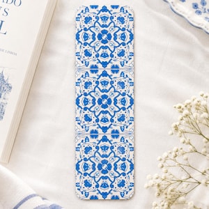 Peut inclure: Un marque-page rectangulaire orné d'un motif répétitif de carreaux bleus et blancs. Le design se compose de trois sections carrées empilées, chacune présentant un motif botanique symétrique et complexe en encre bleue sur fond blanc.