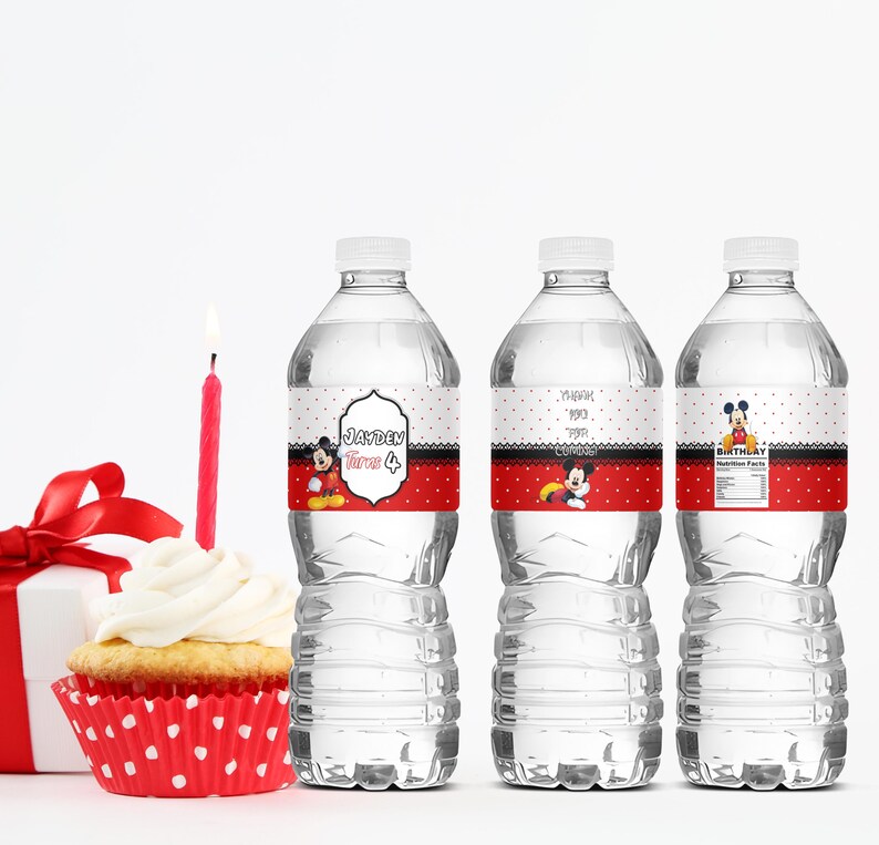 May include: Three clear water bottles with custom labels featuring Mickey Mouse designs. The labels have a red and white polka dot pattern, with text that reads "Jayden turns 4" and "Birthday". A cupcake with a lit candle and a wrapped gift are also in the image.