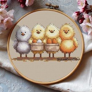 May include: Cross-stitch embroidery in a wooden hoop. The design shows four chicks in yellow, orange, and grey, with two holding baskets of eggs. The background is beige. The text "SkyLarkCrossStitch" is at the bottom of the design.