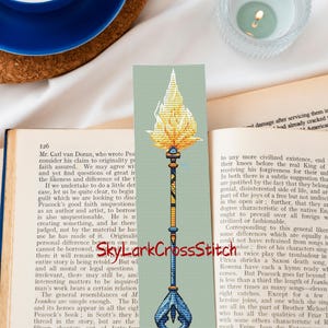 Boekenlegger geheimzinnige vlam, toverstaf betoverd vuur, relikwie fantasie, lichtgevend magisch symbool, dramatische spreukkunst, digitaal kruissteekpatroon