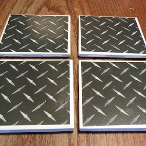 May include: Set of four square ceramic coasters with a diamond plate pattern in black and white. The coasters have a white border.