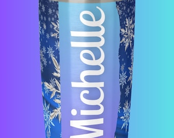 Könnte beinhalten: Ein Edelstahlbecher mit einem transparenten Deckel. Der Becher hat einen blau-violetten Farbverlauf mit weißen Schneeflocken. Der Name "Michelle" ist vertikal in Weiß aufgedruckt.