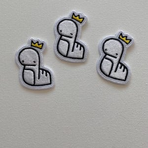May include: Three white embroidered iron-on patches of a cartoon creature wearing a yellow crown.