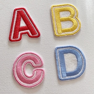 May include: Four felt letters, A, B, C, and D, with white outlines. The letters are red, yellow, pink, and blue.