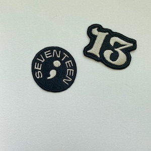 May include: Two black embroidered patches. One is round and says "SEVENTEEN" with a semicolon in the middle. The other is a white number "13" in a stylised font.