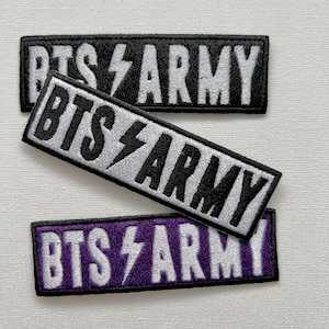 Op de afbeelding: Drie geborduurde patches met de tekst "BTS ARMY" in witte letters op een zwarte, zilveren en paarse achtergrond. Elke patch heeft een bliksem symbool.