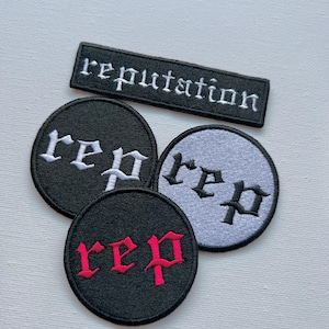 Può includere: Toppe ricamate con le parole "reputation" e "rep". La toppa "reputation" è rettangolare con testo bianco su sfondo nero. Le toppe "rep" sono circolari, con testo bianco o rosa su sfondi neri o grigi.