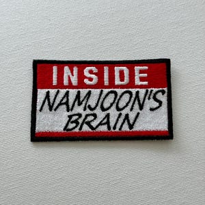 May include: A white and red embroidered patch with black outlining. The patch says "Inside Namjoon's Brain" in black lettering.