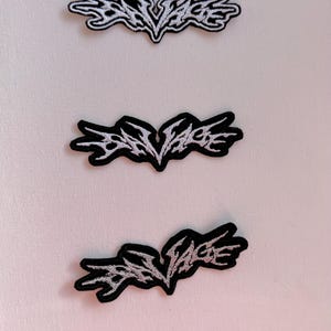 Peut inclure: Trois patchs brodés noir et blanc avec le texte "Bad Vibes" dans une police de caractères stylisée.