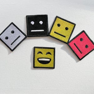 Puede incluir: Cinco parches bordados para planchar con diferentes expresiones faciales. Los parches son negros, amarillos, grises, rojos y amarillos. Las expresiones son neutras, neutras, neutras, tristes y felices.