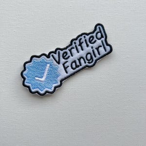 May include: White embroidered patch with a blue tick and the text "Verified Fangirl" in black.