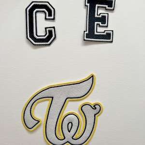 May include: Three iron-on patches, one black letter "C", one black letter "E", and one white letter "T" with a yellow outline.