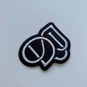 May include: Black and white embroidered patch with the letters "OD" in a stylized font.