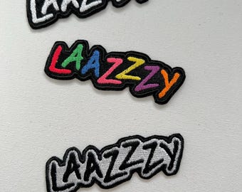 May include: Three embroidered iron-on patches with the word "LAAZZY" in different styles. The top patch has white lettering on a black background. The middle patch has rainbow lettering on a black background. The bottom patch has gray lettering on a black background.