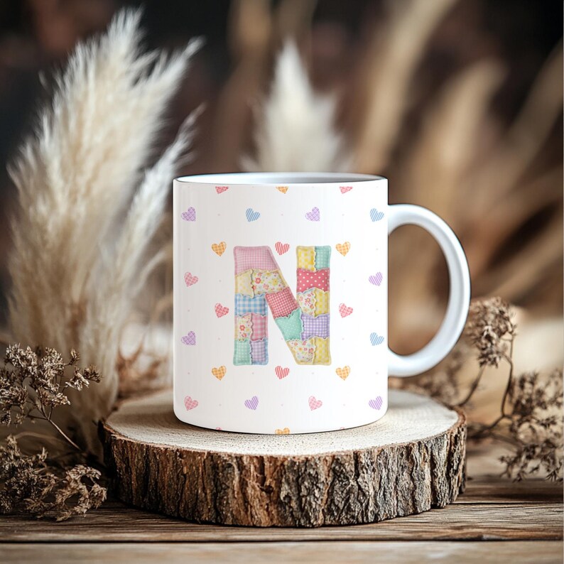 May include: A white ceramic mug with a black handle and the text "But First, Coffee" in a bold, black font. The mug is set against a blurred background. The mug is approximately 10 cm tall.