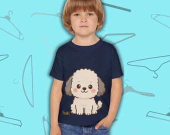May include: A navy blue toddler t-shirt featuring a cartoon poodle illustration. The poodle is white with gray ears and a pink blush. The word "Tsuki" is printed at the bottom of the graphic. The child is wearing blue jeans.