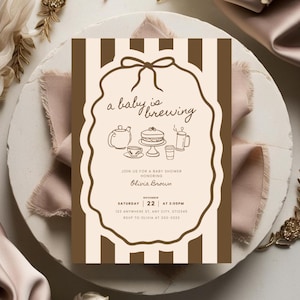 May include: A baby shower invitation with a brown and cream color scheme. The invitation features the text "a baby is brewing" in a decorative frame, along with illustrations of a teapot, cake, and coffee. The invitation is for Olivia Brown.