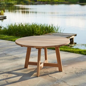 Op de afbeelding: Een ronde houten tafel met een natuurlijke afwerking en een eenvoudig, stevig ontwerp. De tafel heeft een breed, vlak blad en vier poten die met een dwarsbalk zijn verbonden. De tafel is gemaakt van teak hout en is perfect voor buitengebruik.