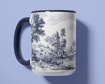 May include: White ceramic mug with a dark blue handle and rim. The mug features a detailed black and white pastoral scene with trees, figures, and a body of water. The mug is set against a light blue background.
