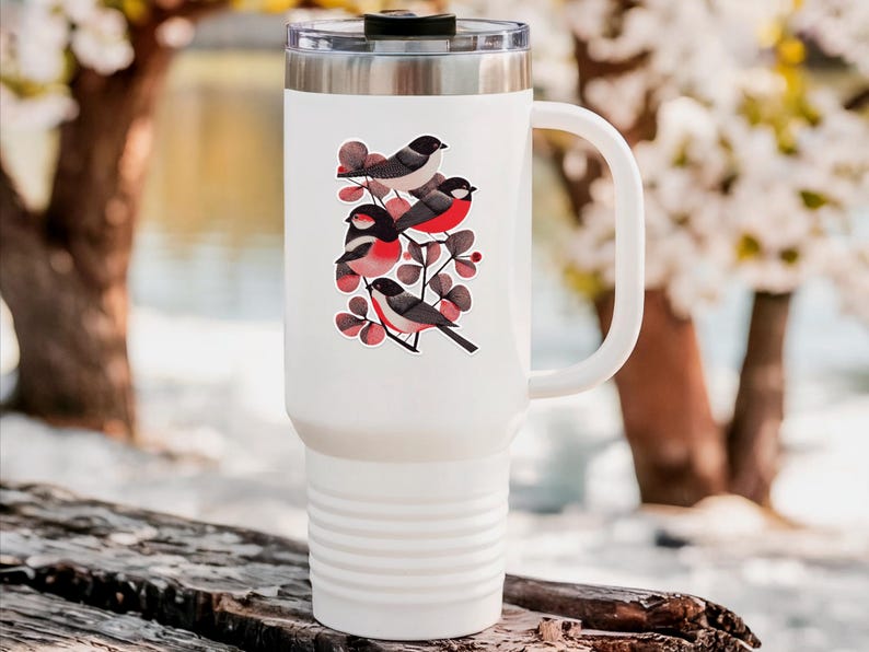 A beautiful and minimal illustration of four finches perched in a tree. Design is black, red and cream, printed on a kiss-cut vinyl sticker with a white border. Sticker is shown on a tall white tumbler in a luxurious outdoor setting.