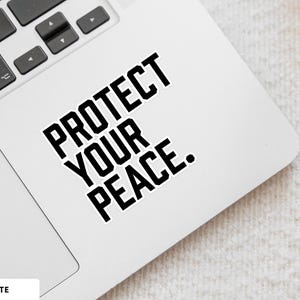 A bold typographic design reading PROTECT YOUR PEACE. Design is printed on a kiss-cut vinyl sticker with a white border. Sticker is shown on an open silver laptop, next to the track pad.