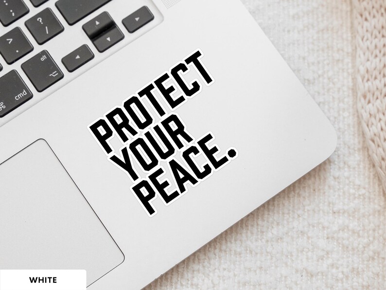 A bold typographic design reading PROTECT YOUR PEACE. Design is printed on a kiss-cut vinyl sticker with a white border. Sticker is shown on an open silver laptop, next to the track pad.
