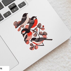 A beautiful and minimal illustration of four finches perched in a tree. Design is black, red and cream, printed on a kiss-cut vinyl sticker with a white border. Sticker is shown on an open silver laptop, next to the track pad.