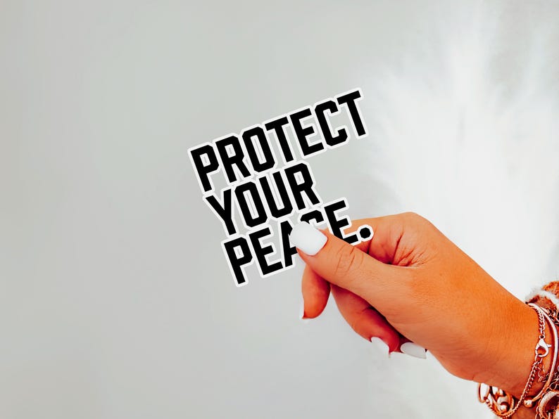 A bold typographic design reading PROTECT YOUR PEACE. Design is printed on a kiss-cut vinyl sticker with a white border. Sticker is being held by a single hand on a neutral, light grey background.