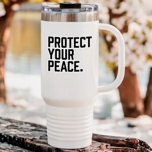 A bold typographic design reading PROTECT YOUR PEACE. Design is printed on a kiss-cut vinyl sticker with a white border. Sticker is shown on a tall white tumbler in a luxurious outdoor setting.
