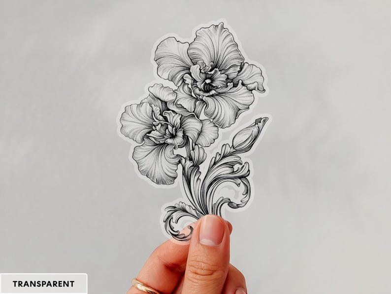 An ornate engraved style rendering of two orchids with elegant flourishes in a balanced, elegant arrangement. Design is printed on a kiss-cut vinyl sticker with a transparent border. Sticker is being held by a single hand on a neutral, light grey background.