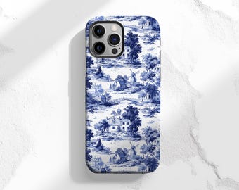 May include: A phone case featuring a blue and white toile design. The pattern depicts a pastoral scene with houses, windmills, trees, and bridges. The case has a glossy finish and a camera cutout.